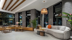 A modern interior with a sofa, dining table, chairs, and a hanging light fixture.