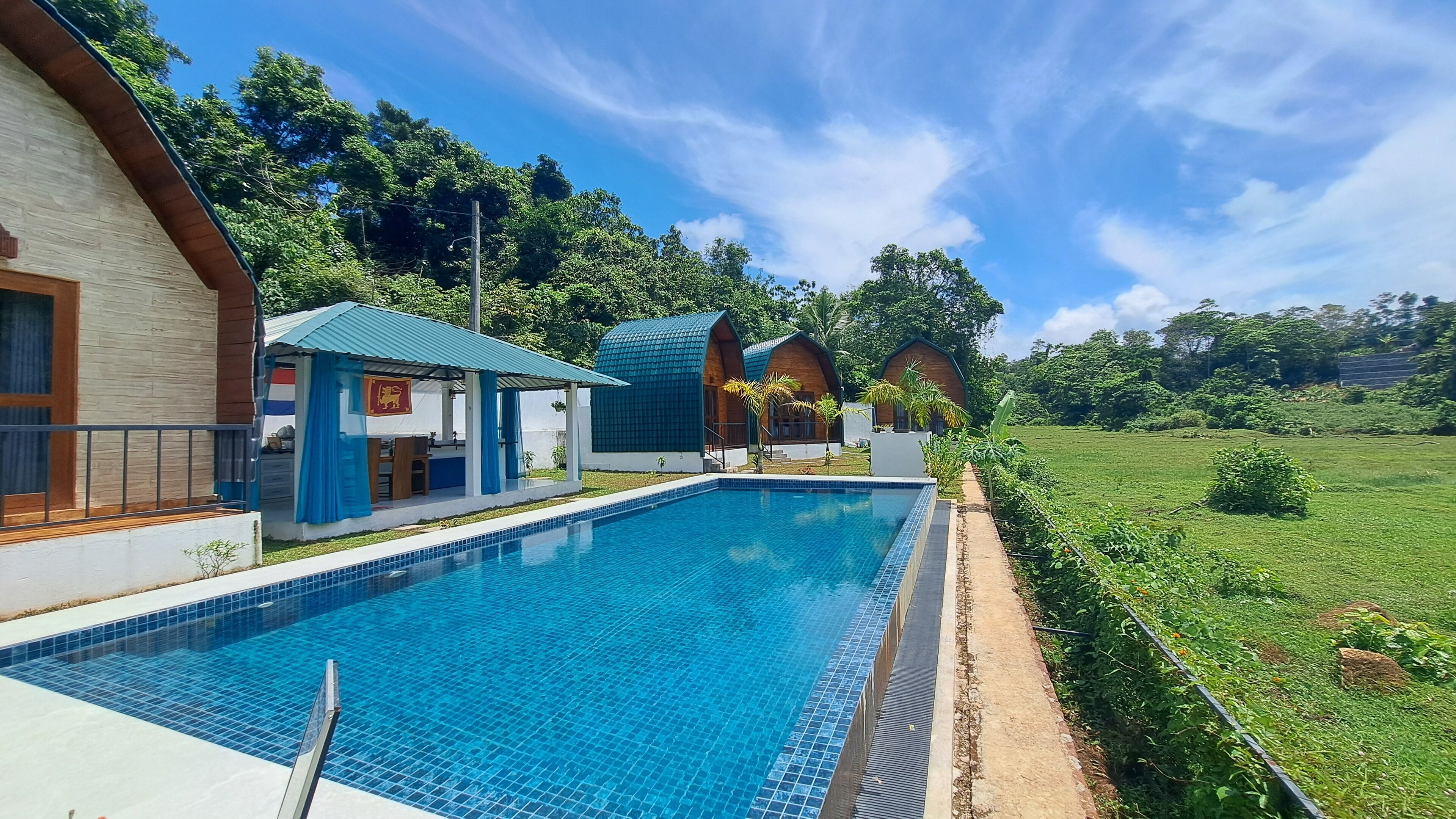 A swimming pool with a tiled edge, surrounded by a grassy area and trees.