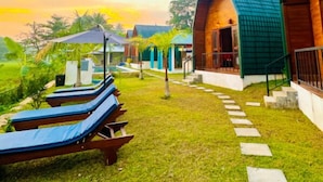 Un resort con cabañas de madera y sillas reclinables sobre un césped.