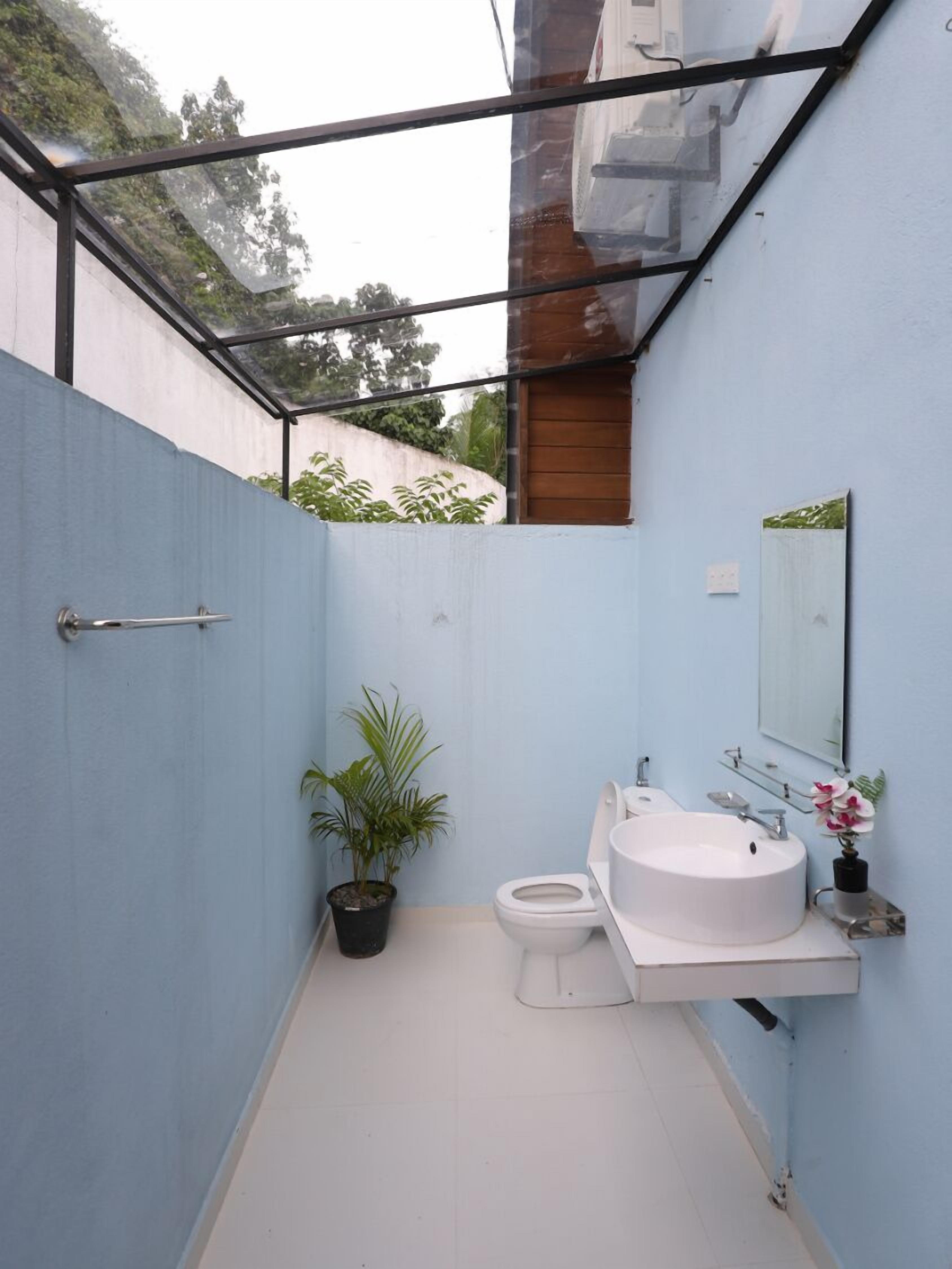 Un baño pequeño con inodoro, lavamanos y plantas en macetas.