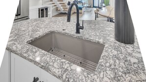 A kitchen with a granite countertop, a black faucet, and a wire rack. - 516 Seascape | Oceanfront Condo with Pool Access in Wild Dunes (Isle Of Palms)