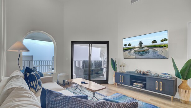 A modern living room with a sofa, coffee table, and a TV mounted on the wall. - 516 Seascape | Oceanfront Condo with Pool Access in Wild Dunes (Isle Of Palms)