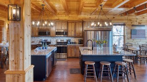 Una cocina amplia con armarios de madera, electrodomésticos de acero inoxidable y una isla grande con taburetes de bar.