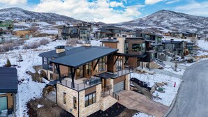 A modern multi-story residential building with a flat roof, large windows, and a balcony.