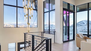 A modern interior with large windows, a staircase, and a view of a snowy landscape.