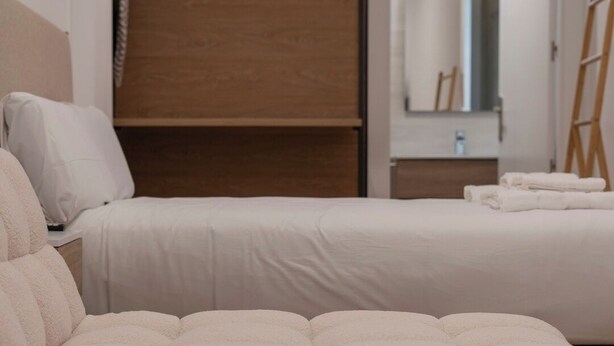 Ein Hotelzimmer mit zwei Betten, Holzboden, Spiegel und einem roten Schild an der Wand.