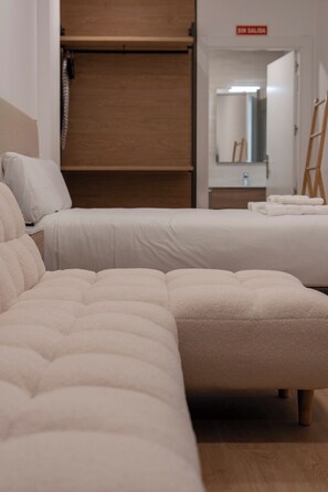 A hotel room with two beds, a wooden floor, a mirror, and a red sign on the wall. - VLC HOST- Molinell 1 (Valencia)