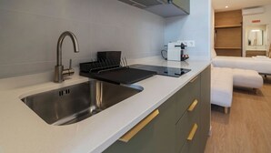 Eine moderne Küche mit Spüle aus Edelstahl, einer Kaffeemaschine und einem Einbauofen.