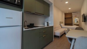 Eine kleine Küche mit einem Liebherr-Kühlschrank, einer Spüle und einer Kaffeemaschine. Es gibt einen kleinen Essbereich mit Tisch und Stühlen.