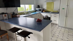 Eine moderne Küche mit blauer Arbeitsplatte, weißen Schränken, einer eingebauten Mikrowelle, einem Gasherd und einem weißen Kühlschrank.