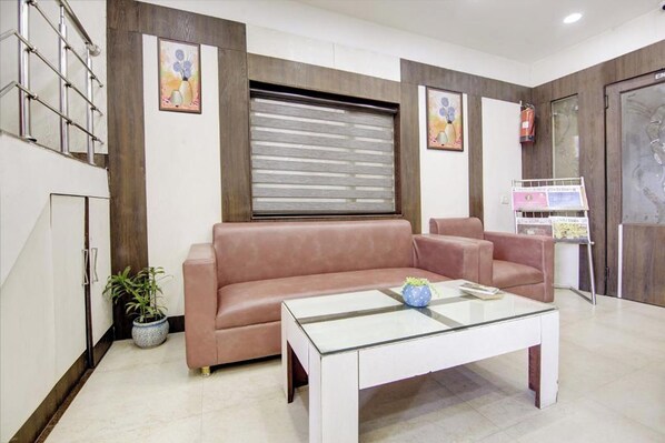 Una sala de estar moderna con un sofá rosa, una mesa de centro de vidrio y un ventanal con persianas.