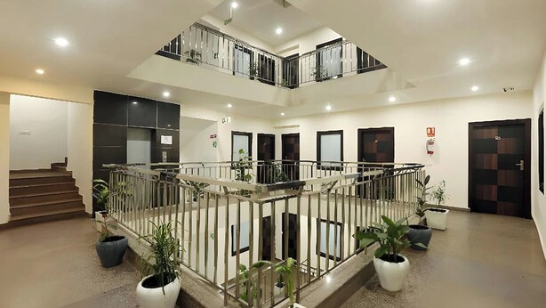 A multi-level indoor space with a central staircase, potted plants, and a railing. - Hotel Sky View (New Delhi)