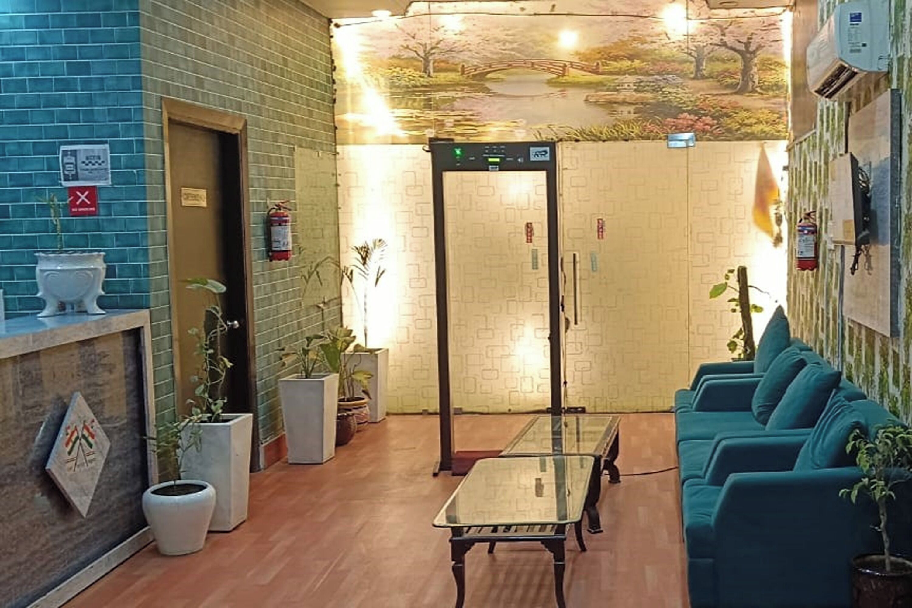 A lobby with a reception desk, a glass-top table, teal sofas, and potted plants.