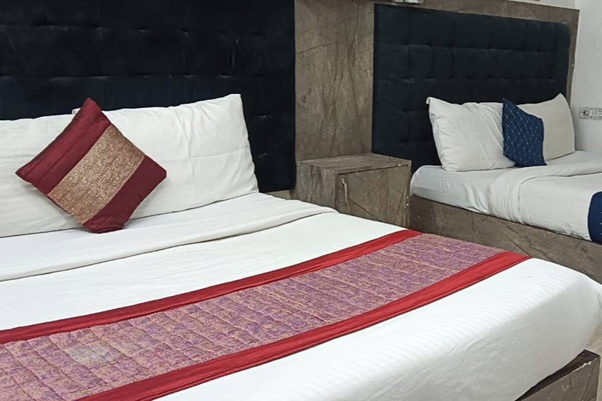 Hotellihuone, jossa on suuri sänky, kaksi yöpöytää ja tumma sängynpääty.