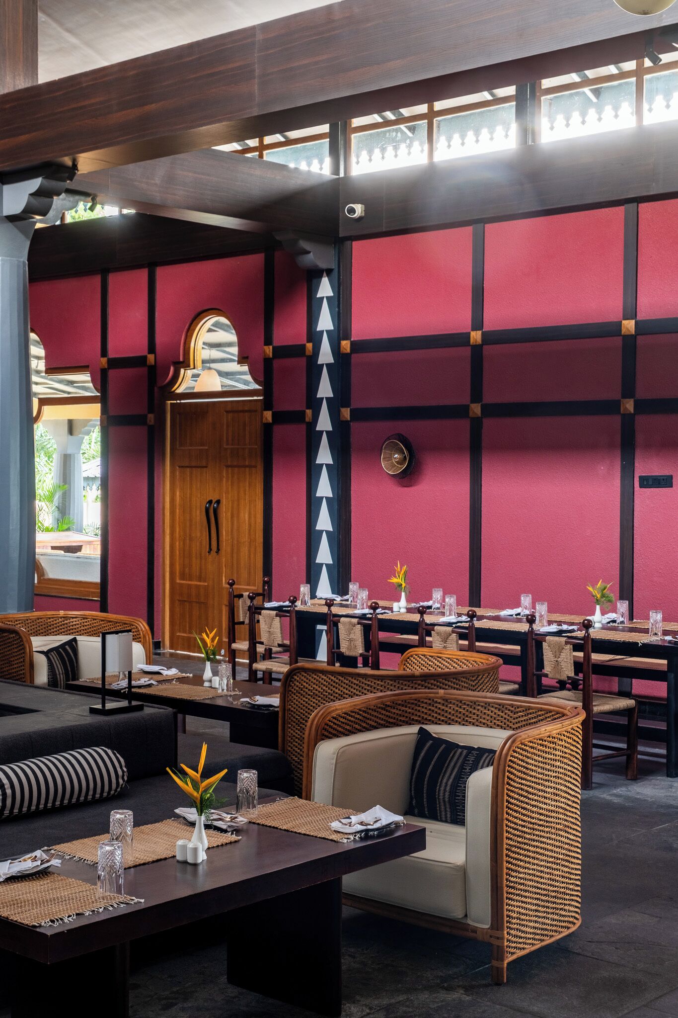 Um restaurante com esquema de cores vermelho e preto, móveis de madeira e vista para o exterior.