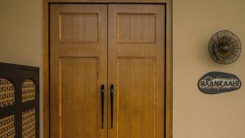 A wooden double door with a decorative arch above it, a metal sign on the wall, and a tiled floor.