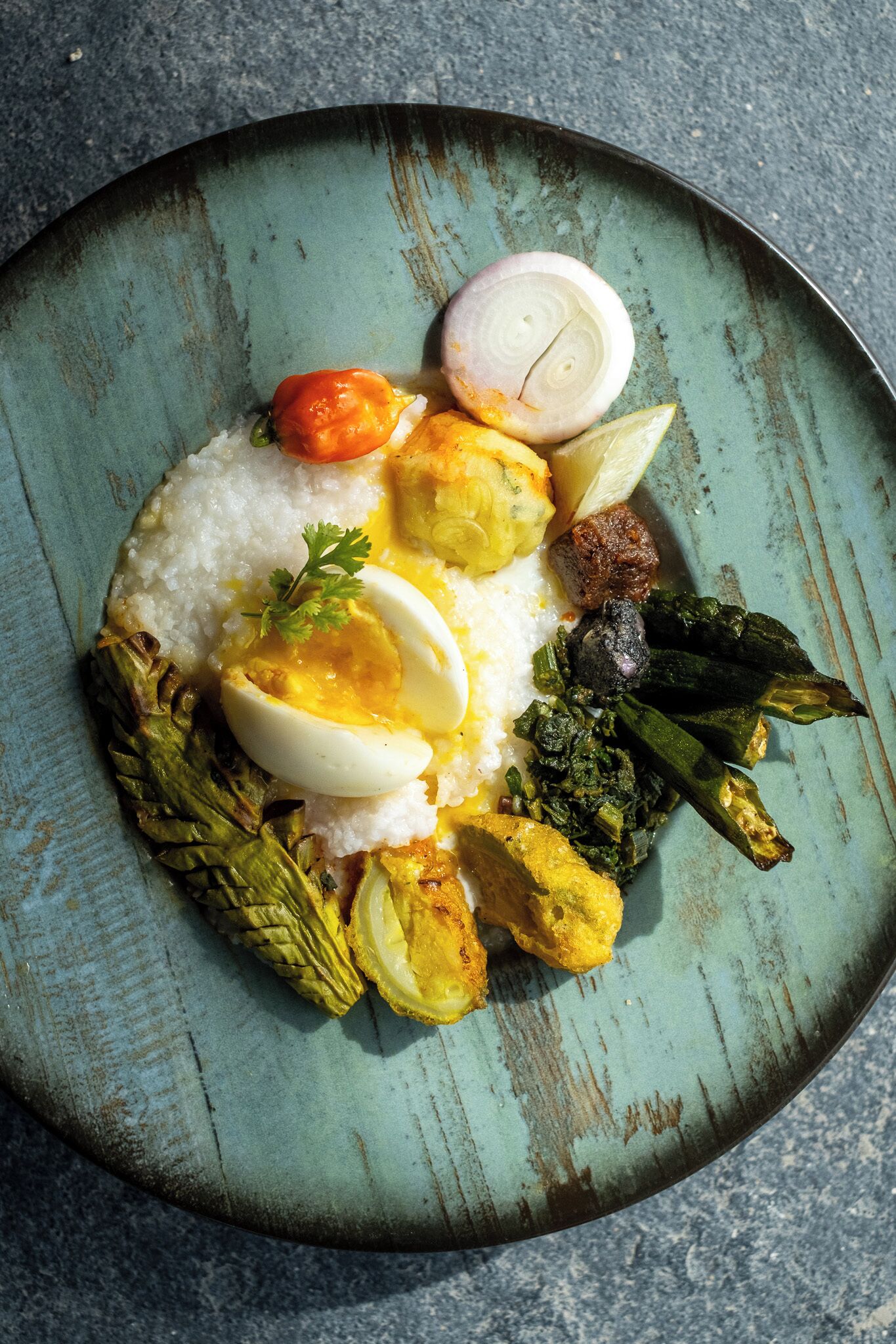 A plate of food with rice, boiled eggs, vegetables, and a piece of meat.