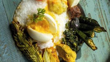 A plate of food with rice, boiled eggs, vegetables, and a piece of meat.