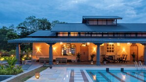 A traditional-style building with a covered patio area, a swimming pool, and outdoor seating. - Rhino and River Wildlife Retreat & Spa, Pobitora - Small Luxury Hotels of the World (Mangaldai)