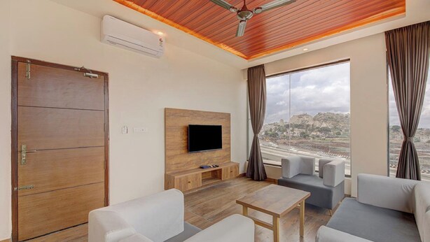 Uma sala de estar moderna com teto de madeira, televisão de tela plana e uma janela grande com vista para a cidade.