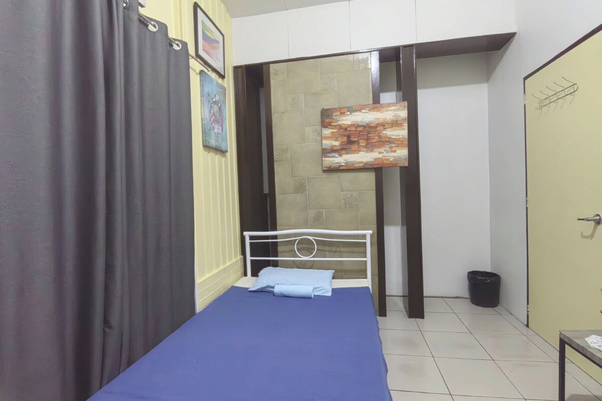 A small, tidy room with a single bed, a small table, and a door.