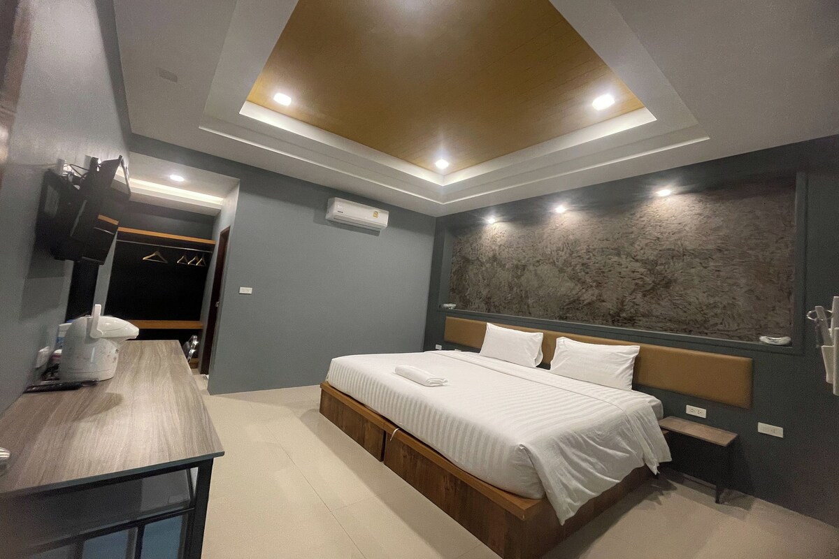 A modern bedroom with a bed, bedside tables, a desk, and a large wall-mounted TV.