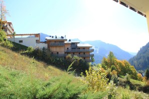 Un immeuble à plusieurs étages, doté de balcons, qui se dresse sur fond de montagnes.