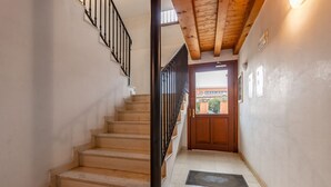 Una escalera con barandilla de madera y balaustradas negras, que lleva a una puerta con un ventanal encima.