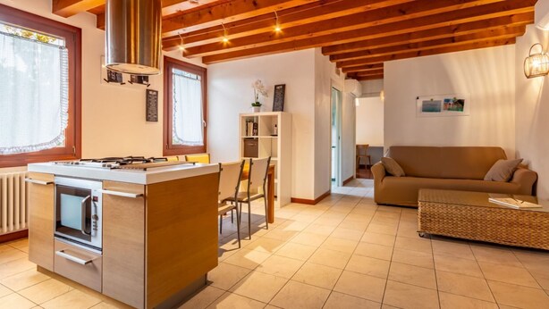 Una cocina moderna con estufa integrada, una isla grande con asientos y un techo de madera.