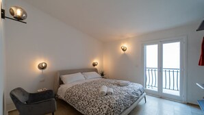 Une chambre à coucher avec un lit, des lampes de chevet, une chaise et un balcon.
