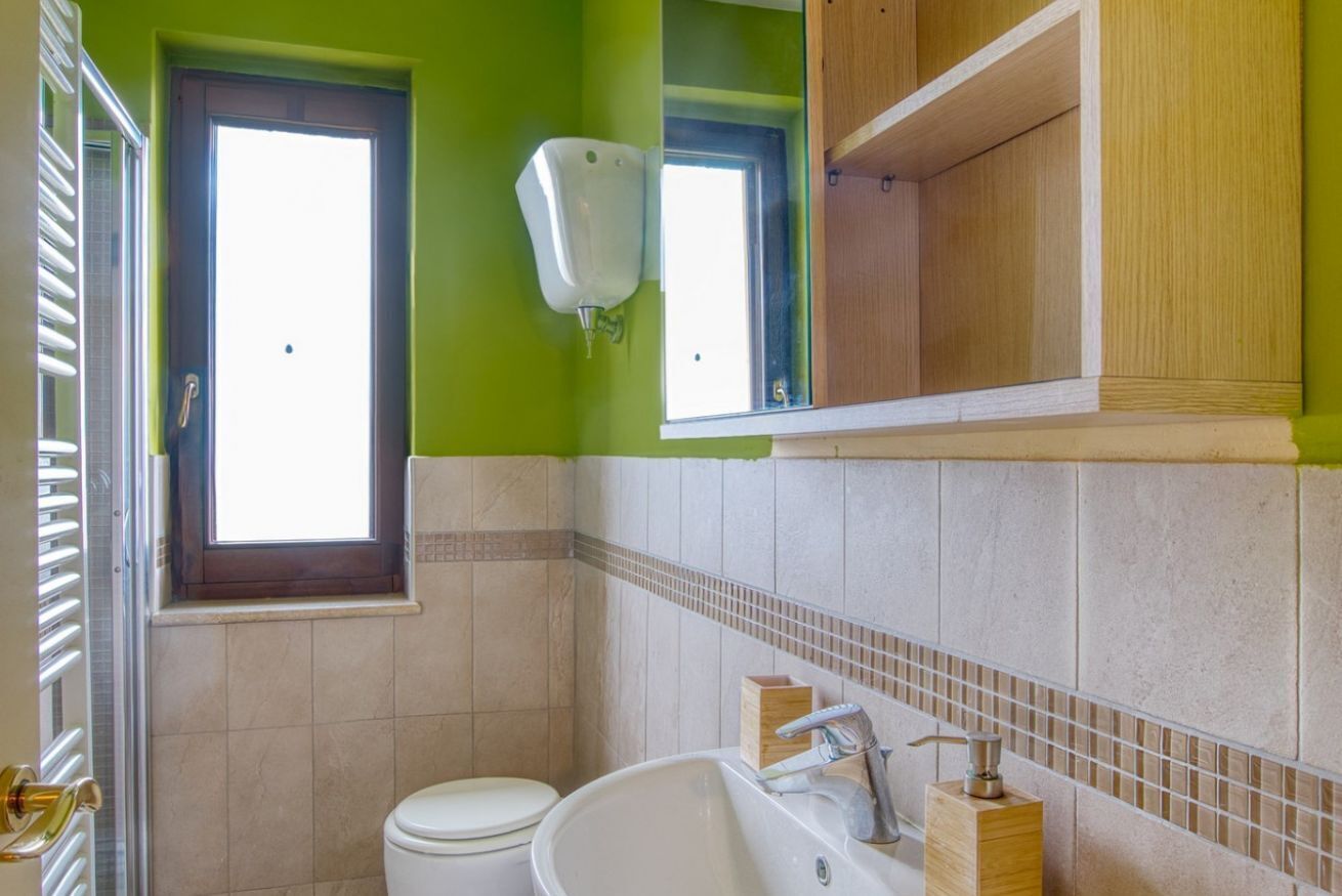 A bathroom with a toilet, sink, and a window.