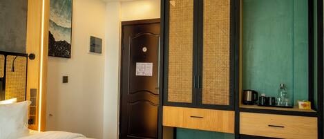 A hotel room with a bed, a wardrobe with a green curtain, and a wall-mounted artwork.