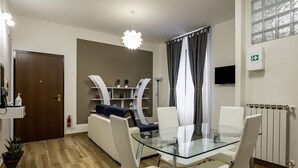 A modern living room with a glass dining table, white chairs, a sofa, and a television. - GuestHost - La Spezia Mon Amour - Pet Friendly (La Spezia)