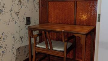 A wooden table with a cushioned bench in a room with floral wallpaper and a herringbone-patterned wooden wall.
