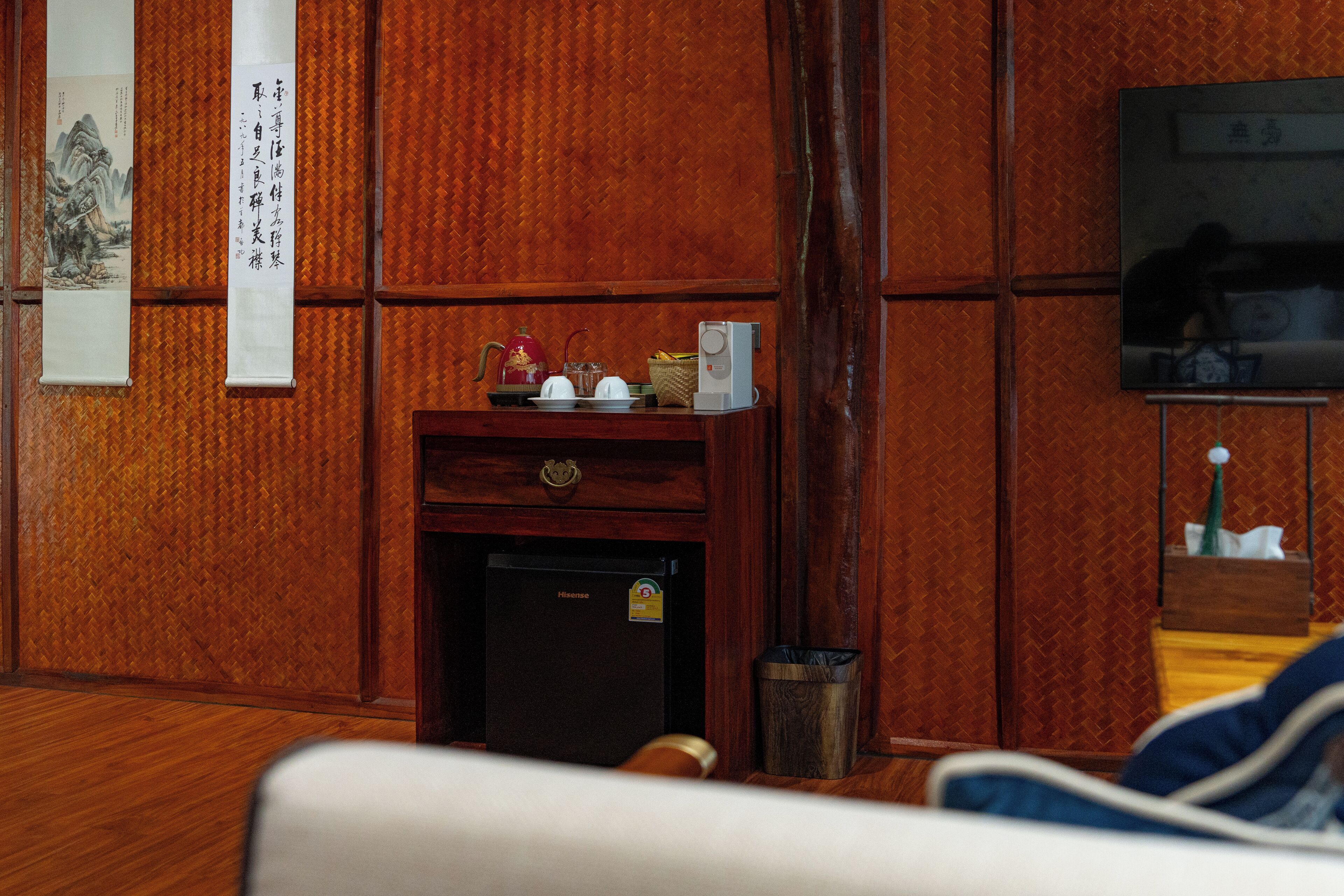 A traditional room with wooden paneling, a small refrigerator, a television, and a decorative wall hanging.