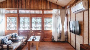 A traditional wooden room with a sofa, table, and TV. - Long Chuan River Kwai (Thong Pha Phum)