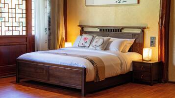 A neatly made bed with a wooden frame, a bedside table with a lamp, and a wall-mounted artwork.