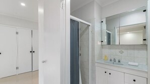 A modern bathroom with a shower, a sink with a mirror, and white cabinets. - Budget 1-Bed Studio Near Top Malls & Transit! (Robertson)