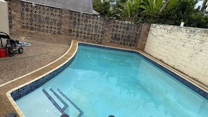 A rectangular swimming pool with a tiled edge and a ladder leading into the water. - Budget 1-Bed Studio Near Top Malls & Transit! (Robertson)