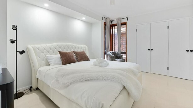 A modern bedroom with a large bed, a wardrobe, and a ceiling fan. - Budget 1-Bed Studio Near Top Malls & Transit! (Robertson)