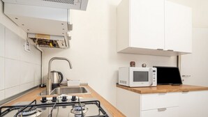 Una cocina moderna con estufa a gas, microondas y armarios blancos.