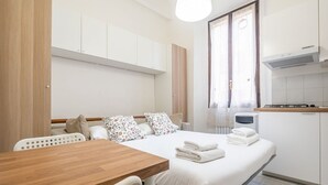 Un dormitorio con cama, mesita de noche y ventana.
