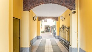Un pasillo con suelo de baldosas, paredes amarillas, un arco de ladrillo y una puerta de metal.