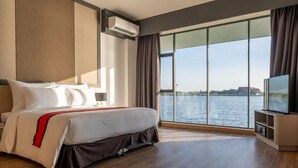 Una habitación de hotel con una cama grande, televisión y vista al agua.