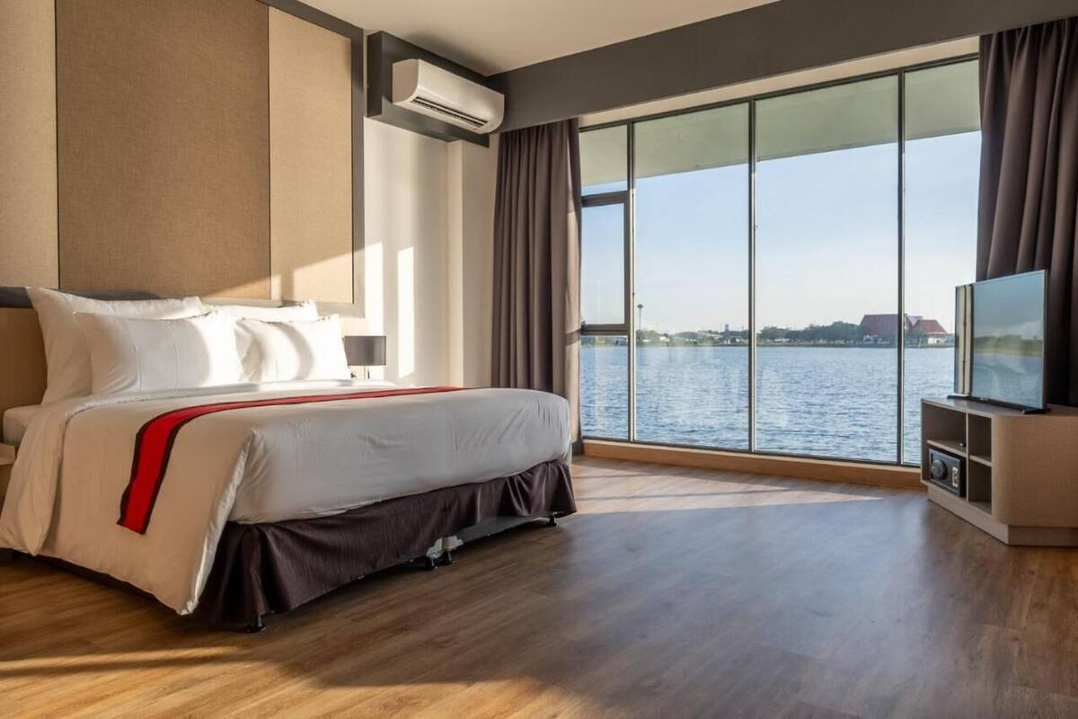 Una habitación de hotel con una cama grande, televisión y vista al agua.