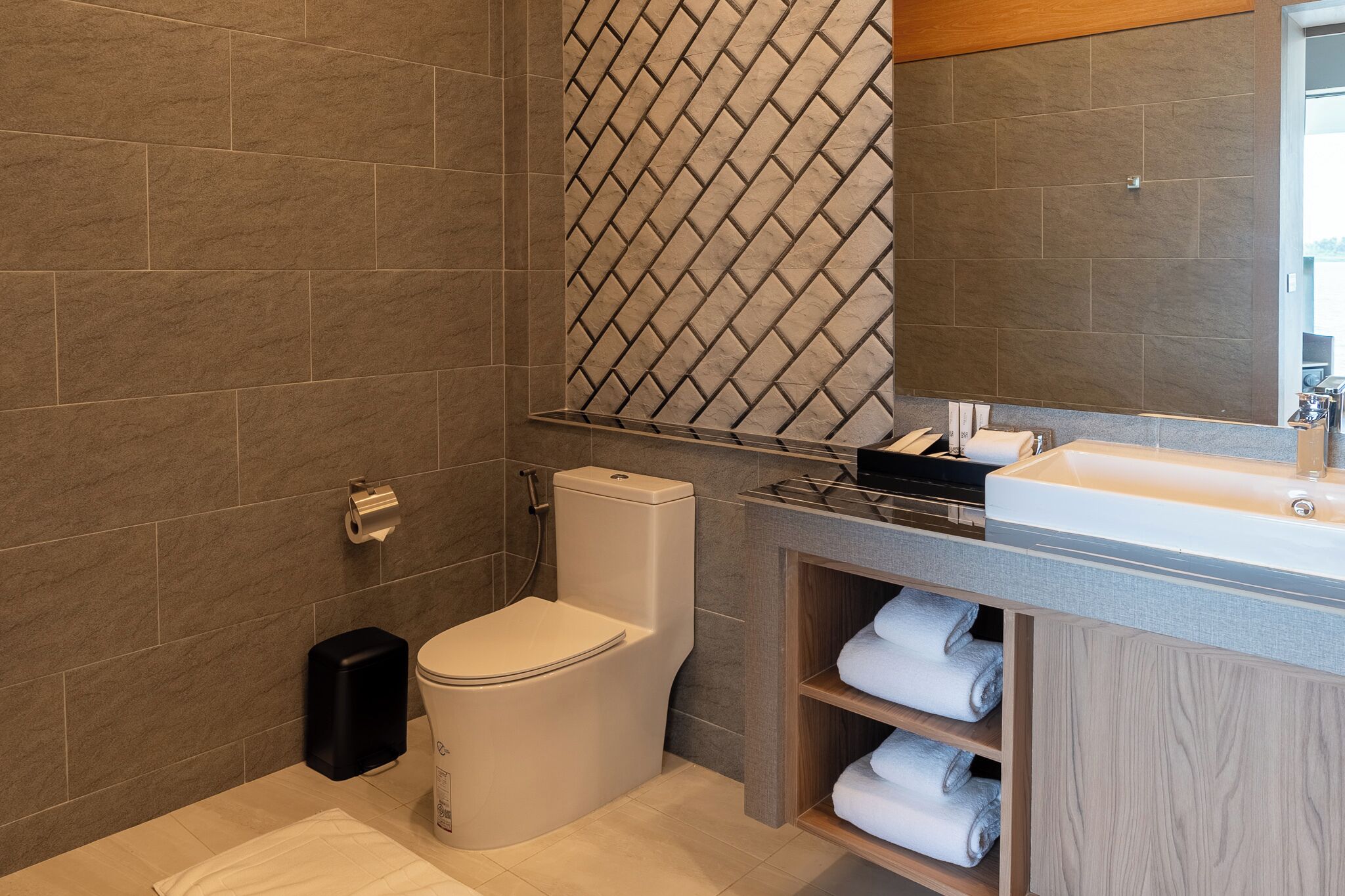 A modern bathroom with a toilet, a sink, and a mirror.