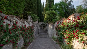Un sentier pavé de pierres, bordé de murs en pierre et agrémenté de rosiers rouges.