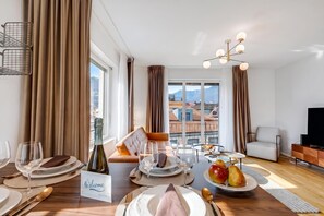 Una habitación bien iluminada con una mesa de comedor lista para una comida, un sofá y un televisor.