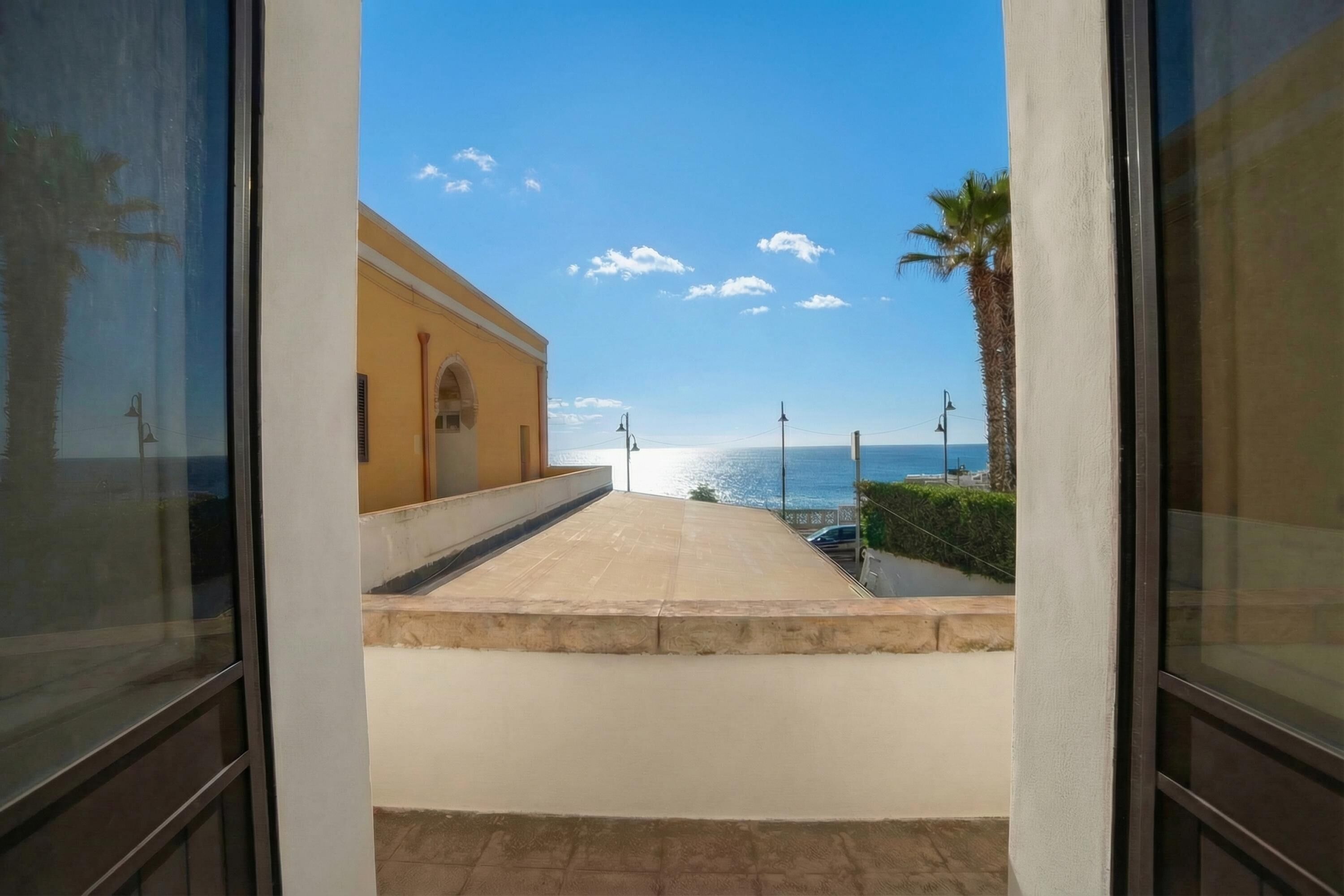 Vista de varanda com vista para a praia e um edifício ao fundo.