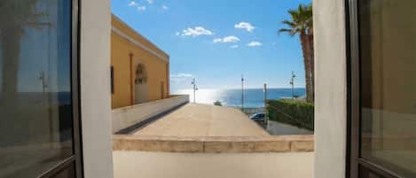 A view from a balcony overlooking a beach with a building in the background.